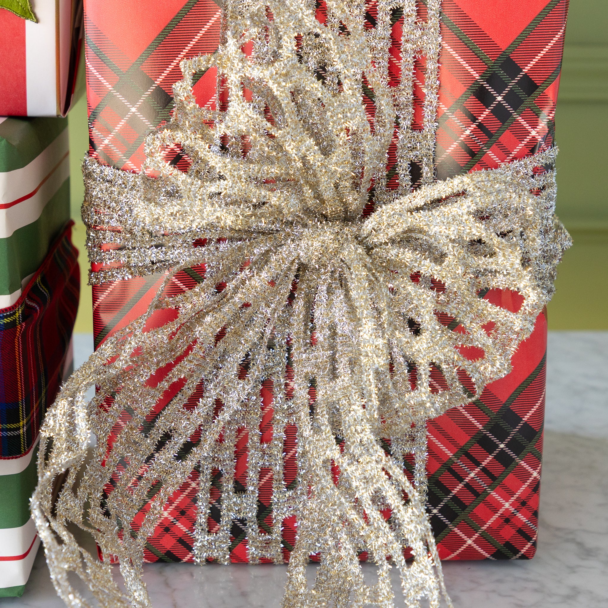 Gift wrapped in red plaid paper with a large silver bow in front