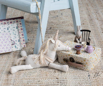 stuffed unicorn playing tea with a stuffed bunny on the floor