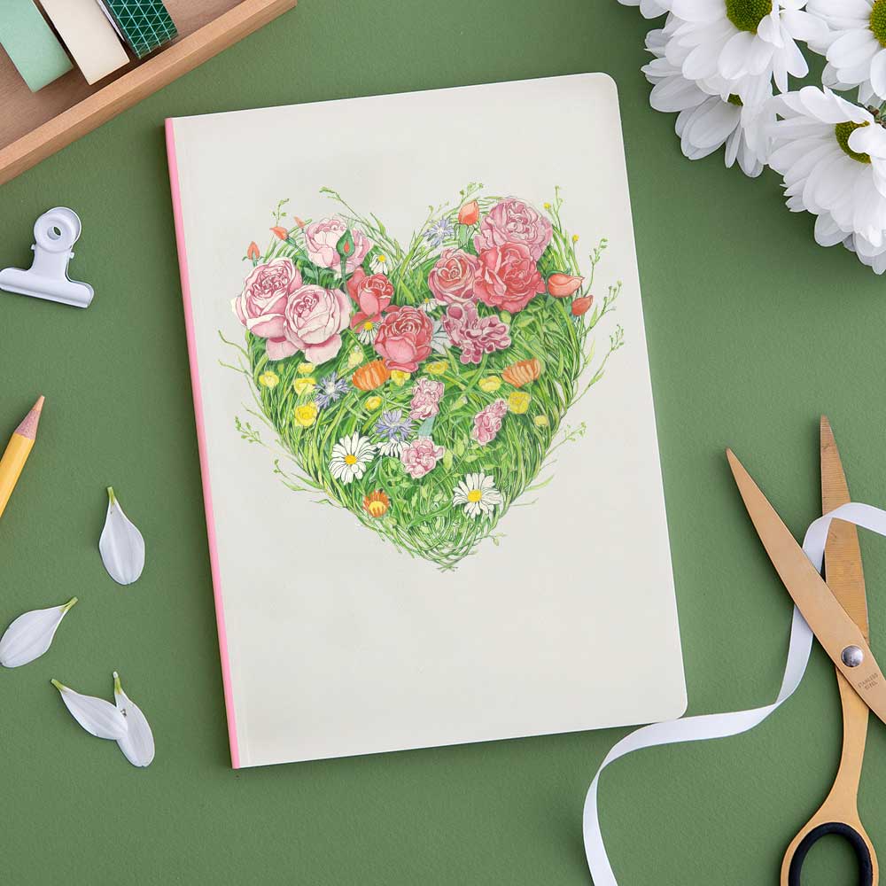 A Grass Heart Perfect Bound Notebook with flowers and scissors on a green background, crafted from luxury cream stock by British papermakers by The DM Collection.
