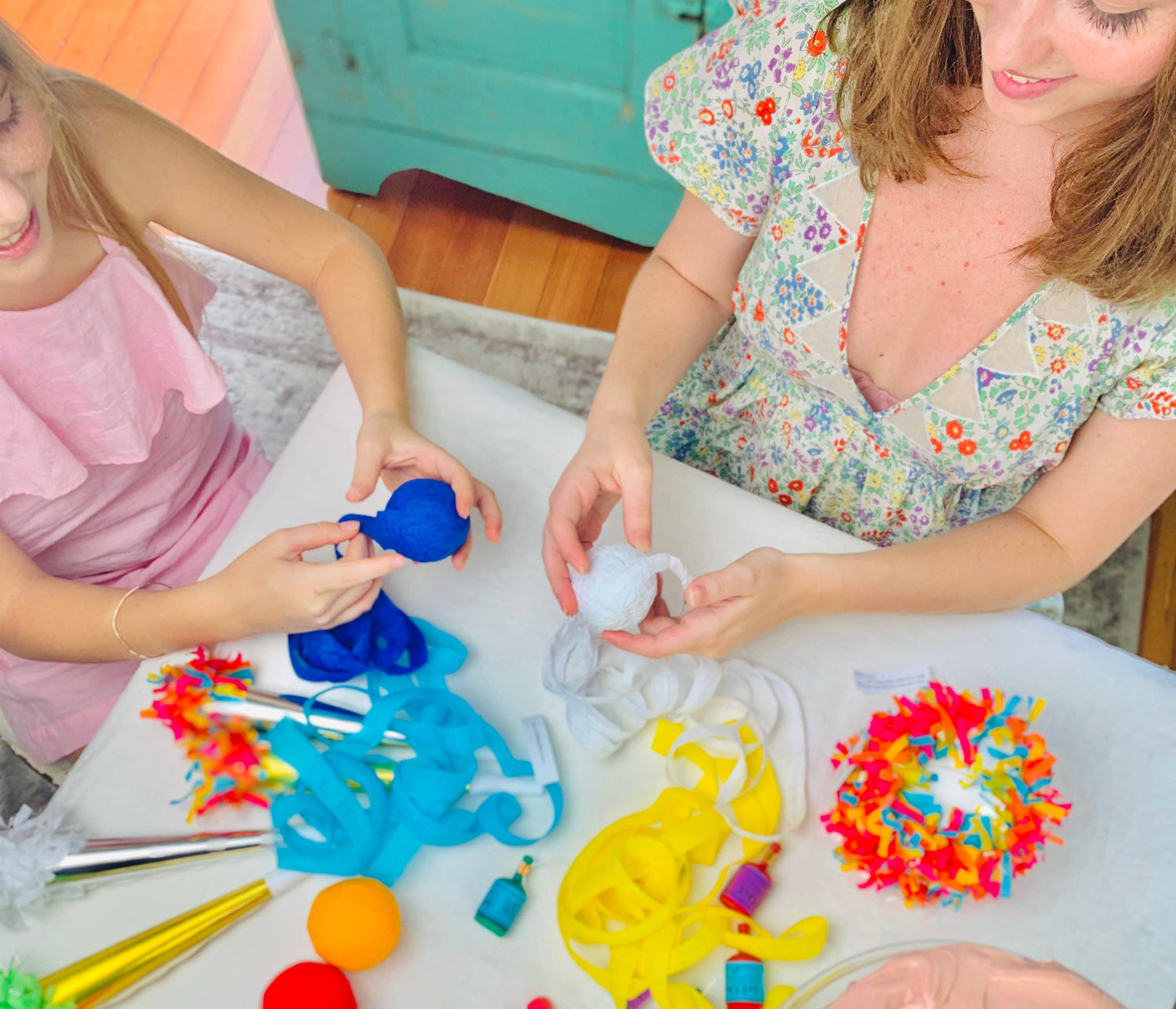 A woman and young girl unwinding surprize balls with contents on the table.