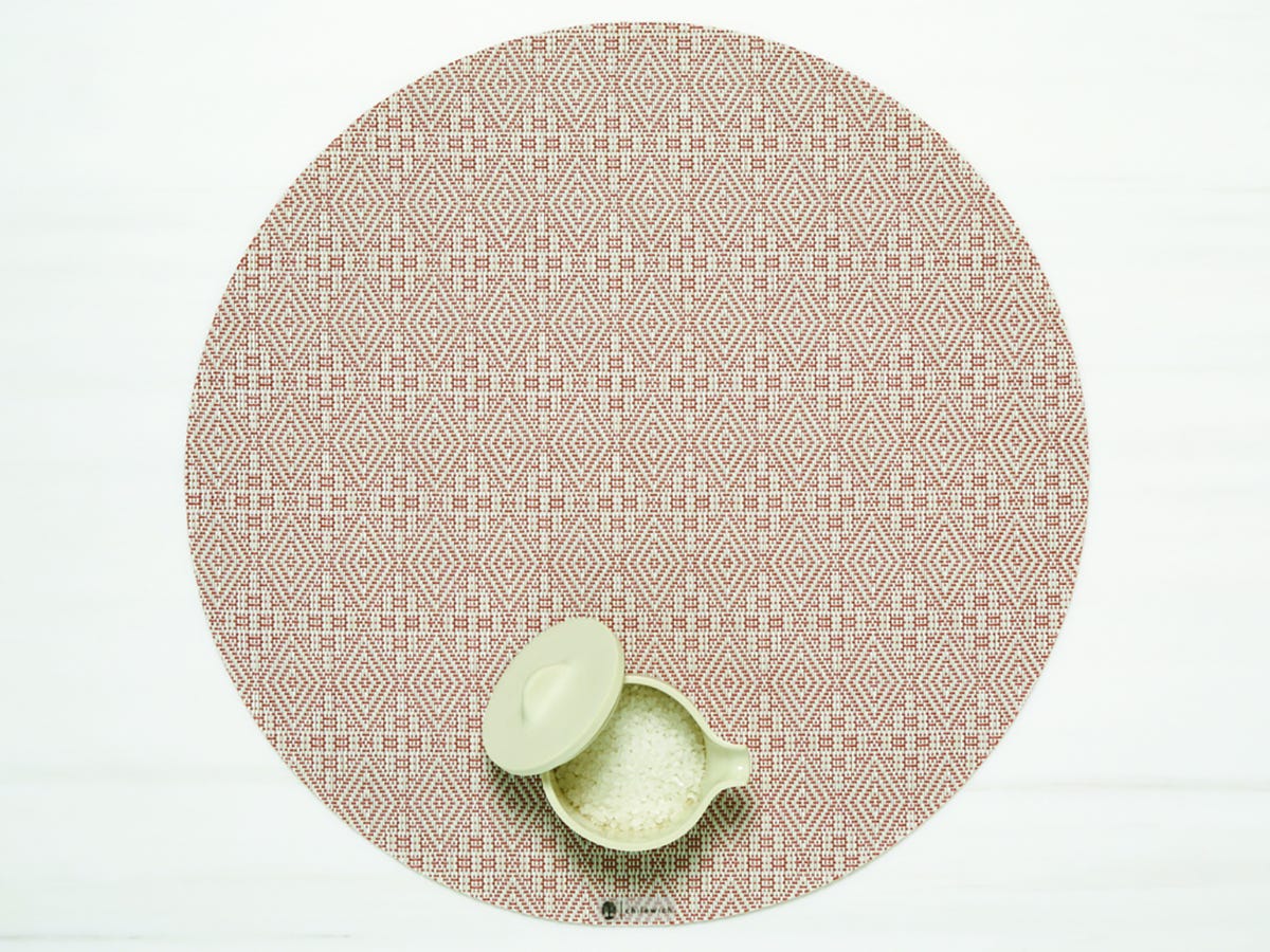 Boxwood Round Placemat with small container of grains on it in the Burnt  Coral