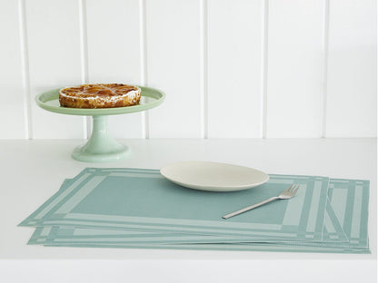 Scattered stack of the Abalone Handkerchief Compact Rectangle Placemat with a plate and fork on top and in the background a cake stand with a pie on it. 