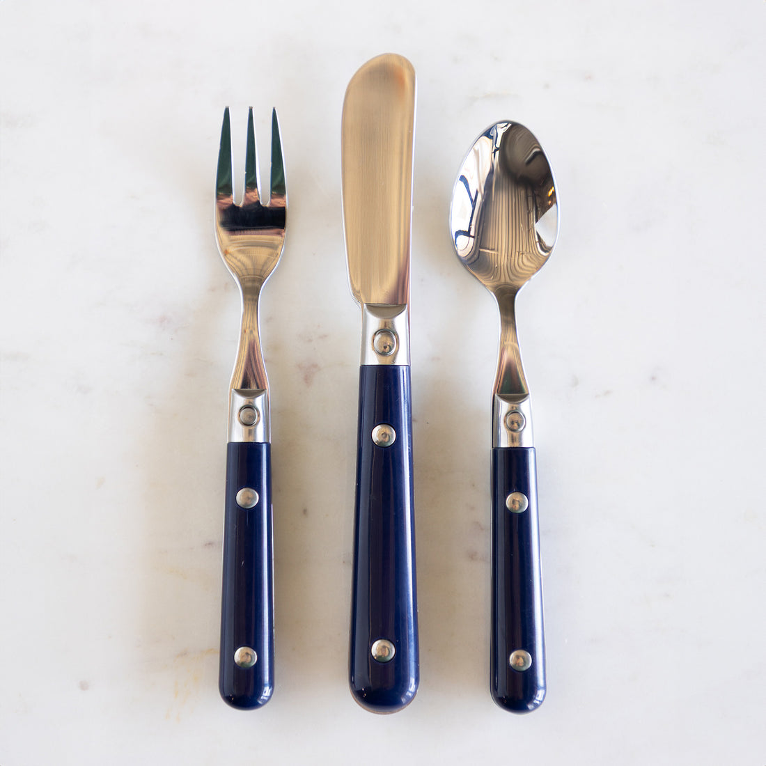 A fork, knife and spoon with navy blue handles.