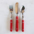 A spoon, knife and fork with red handles. 