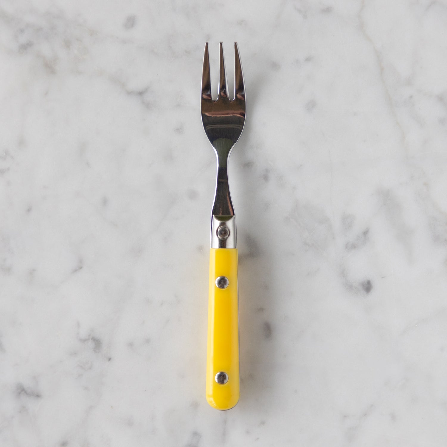 Fork with a yellow handle on a marble background.