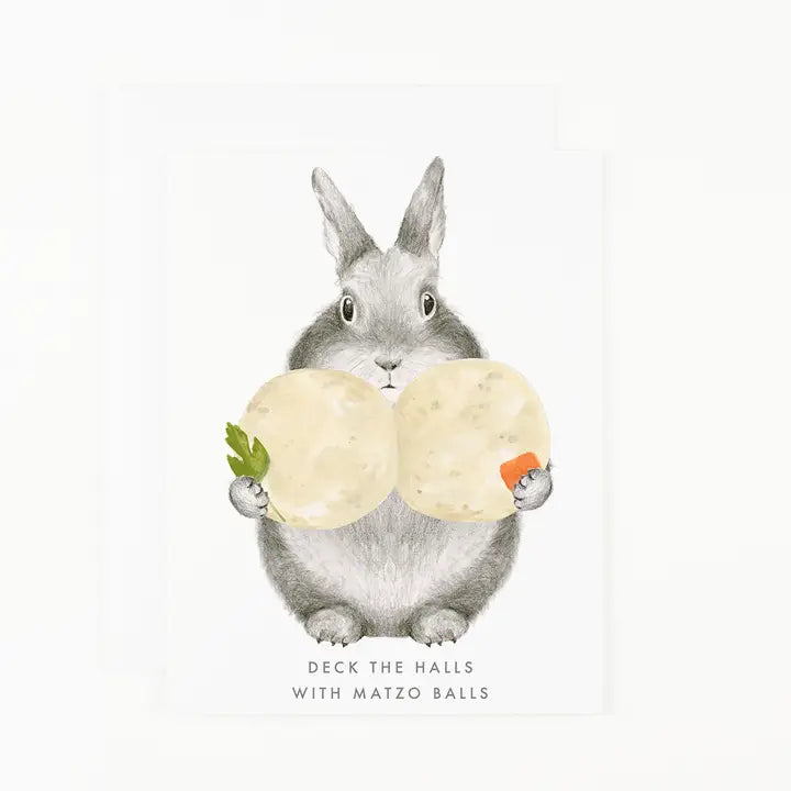 A white greeting card featuring a watercolor illustration of a gray rabbit holding two large, round, pale yellow matzo balls, with the text &