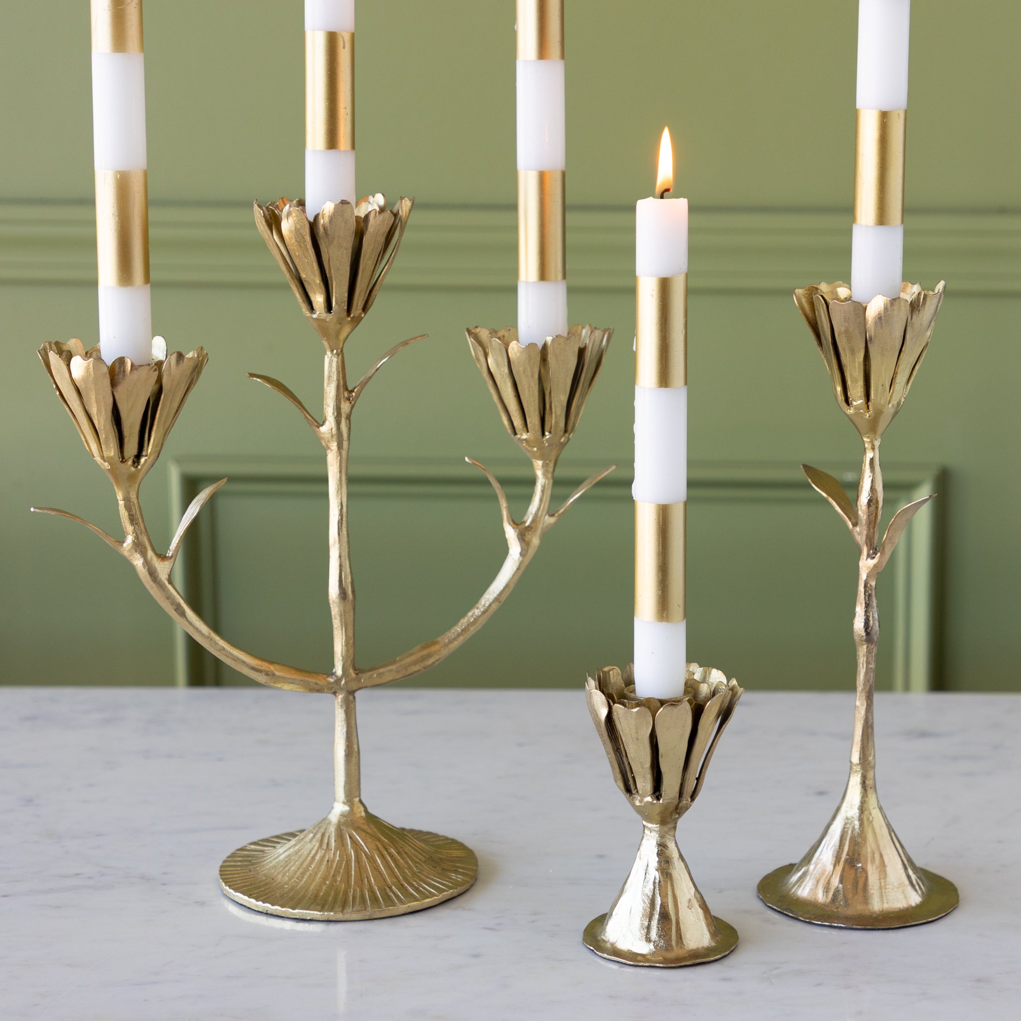 Gold candelabra with candles on a light surface and green background