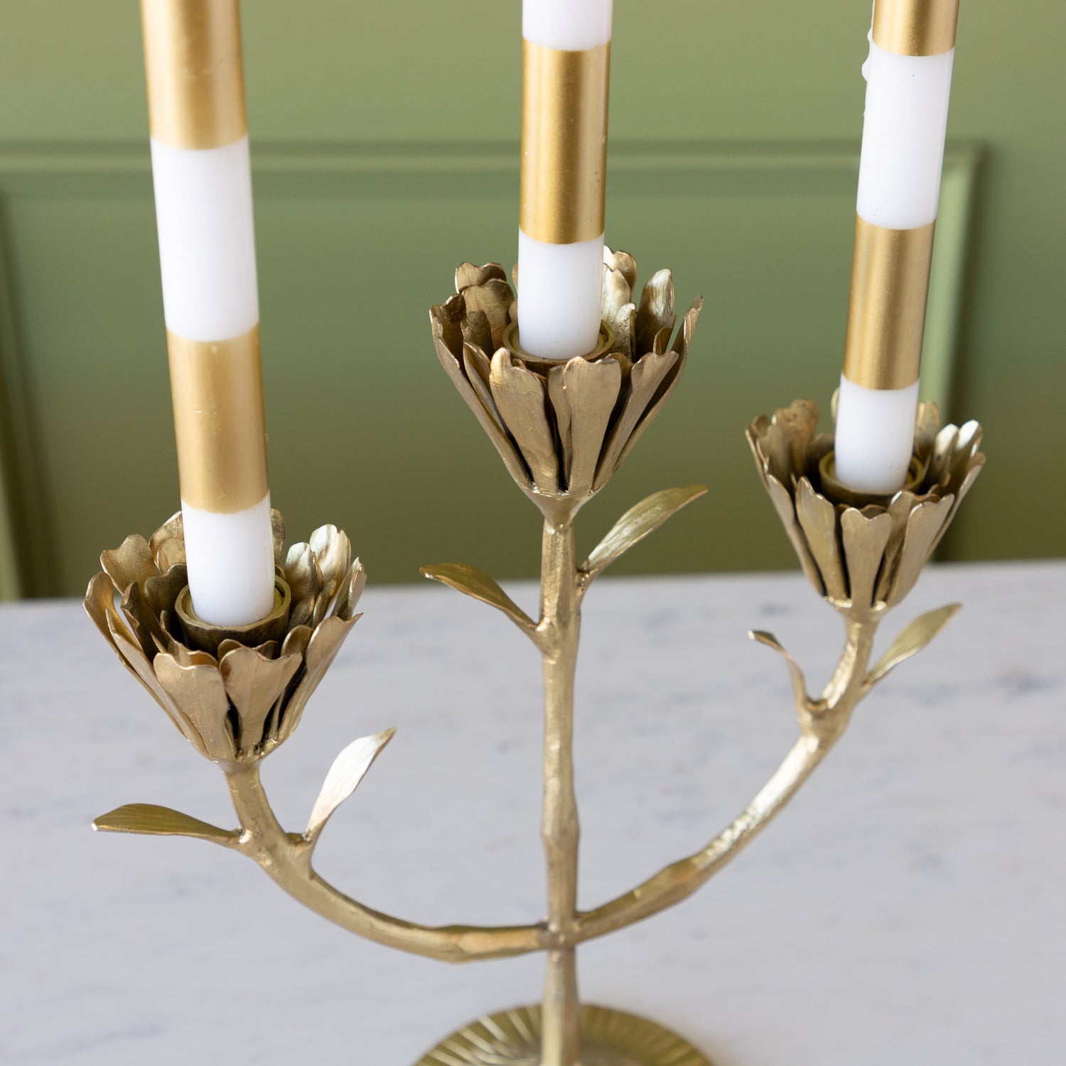 Gold candelabra with white candles on a neutral background.
