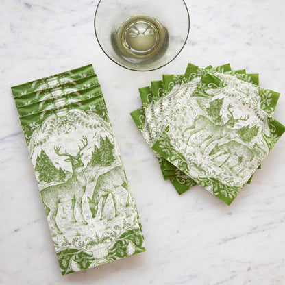 A stack of Fable Toile Guest Napkins and a fanned-out stack of Fable Toile Cocktail Napkins on a table next to a wine glass, from above.