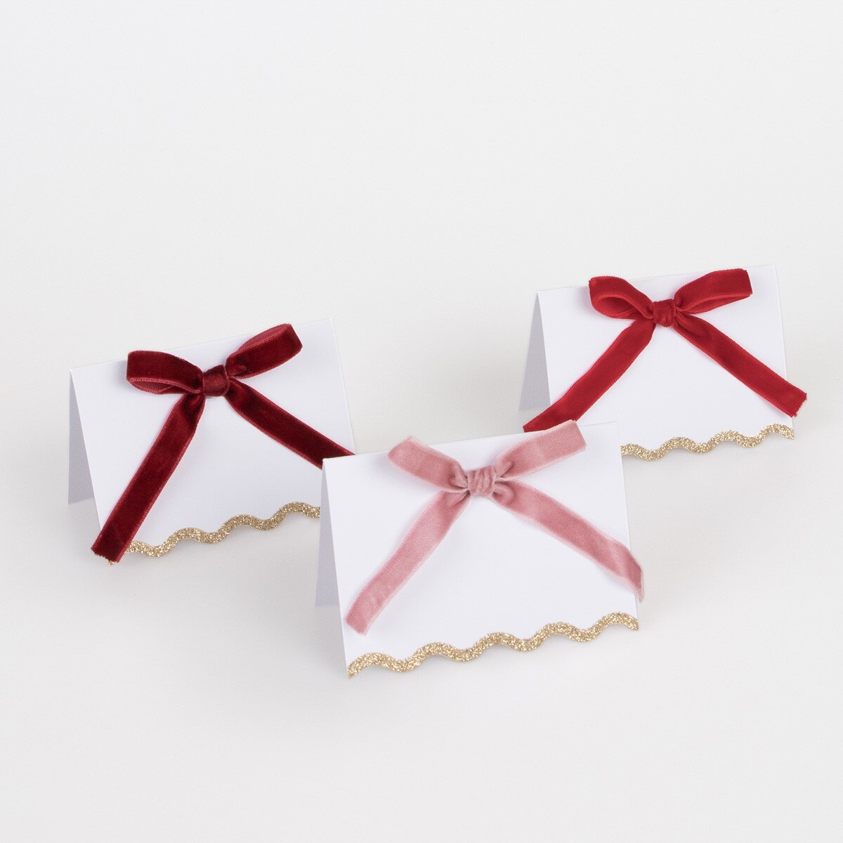 Three place cards with green and blue ribbons on a white background