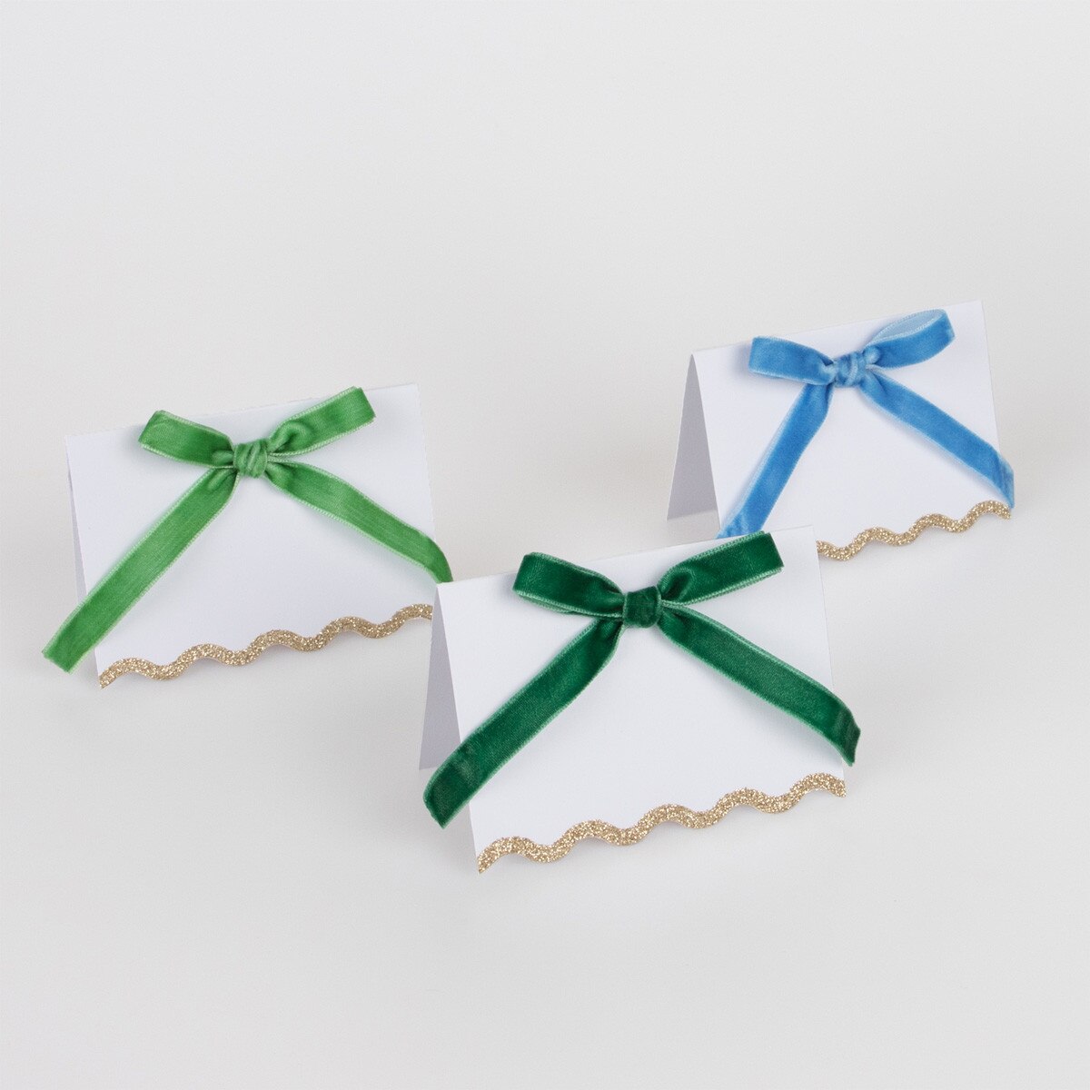 Three place cards with green and blue ribbons on a white background