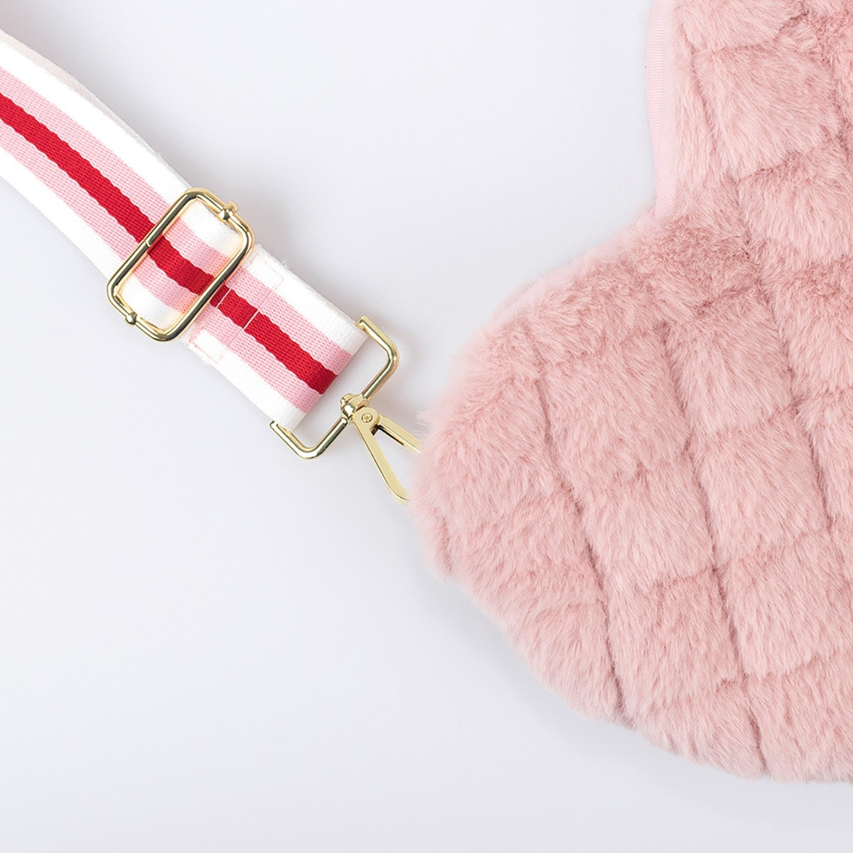 A pink Meri Meri plush heart-shaped bag with a red strap.