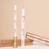 Two white candles with red decorative elements on a beige background