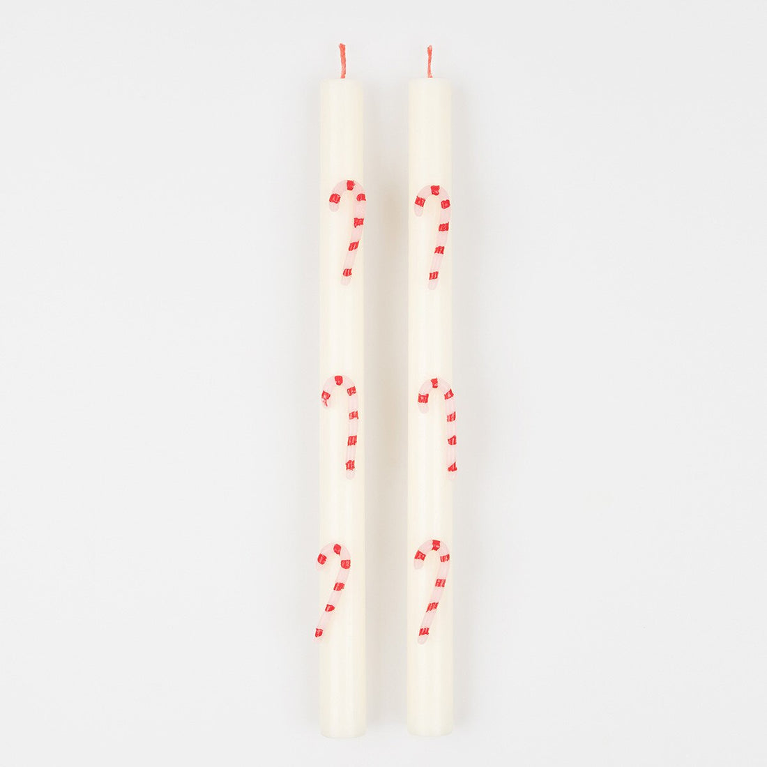 Two white taper candles with red candy cane designs printed on them, shown against a plain white background.
