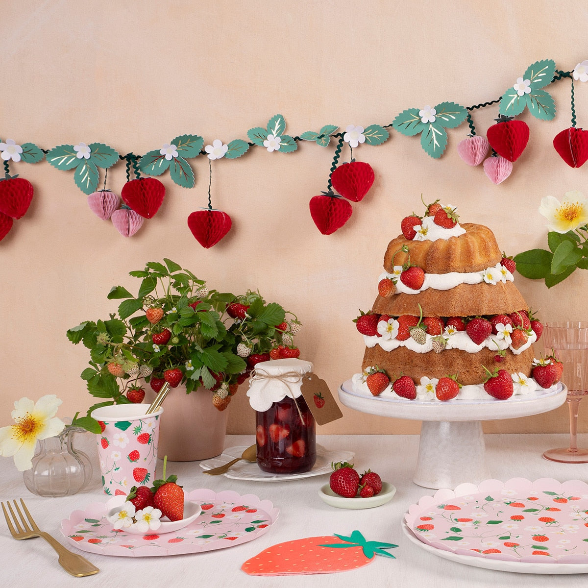 Decorative table setting with a cake, plants, and colorful plates on a beige background.