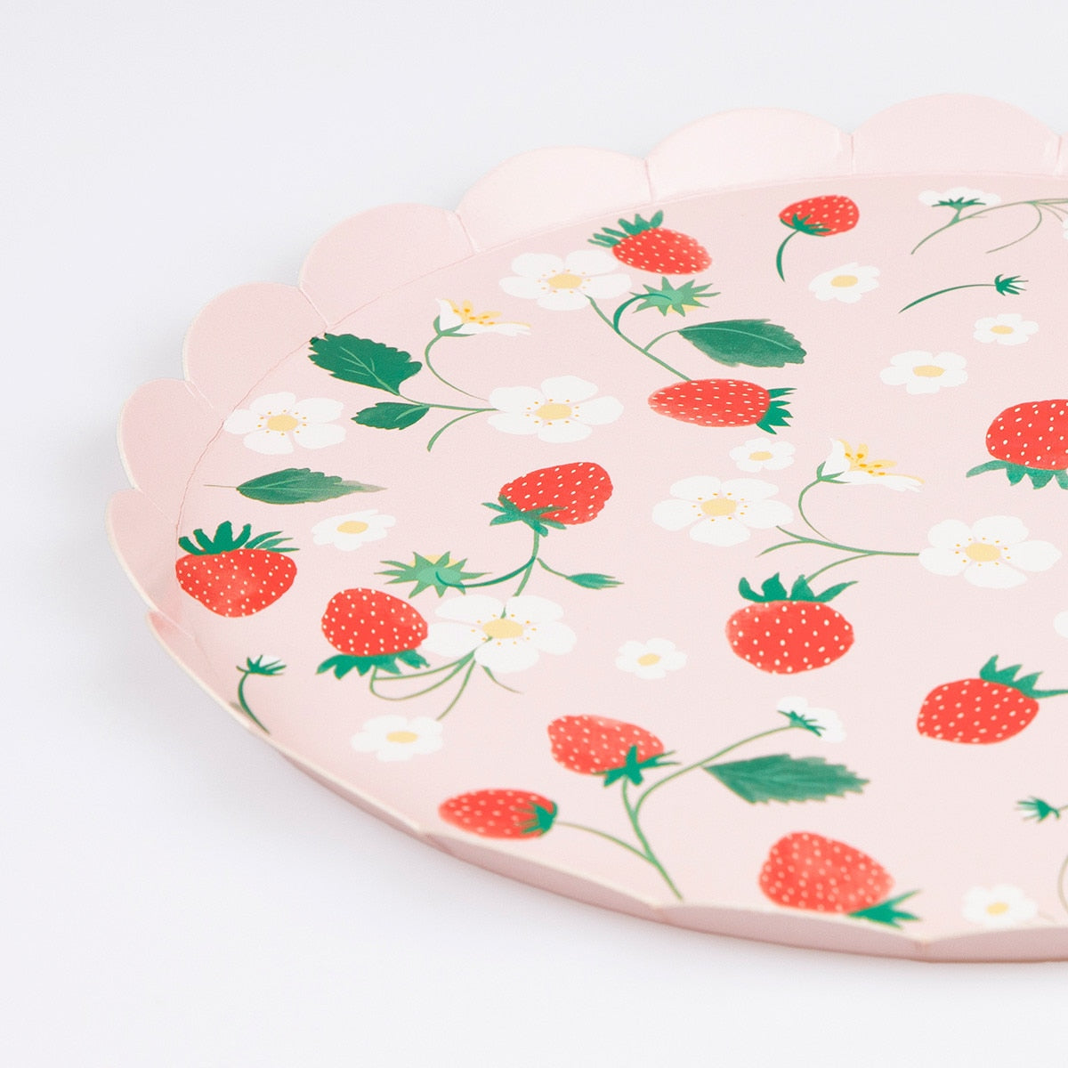 Pink paper plate with strawberry and flower pattern on a white background.