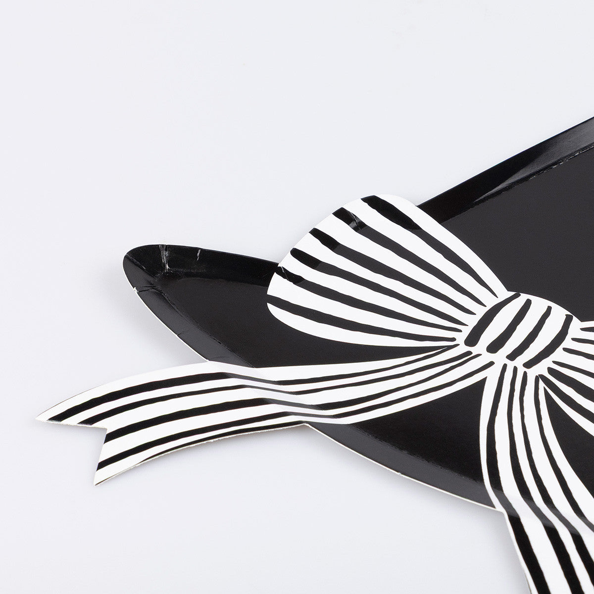 Black witch hat shaped plate with a large white bow on a light gray background. 