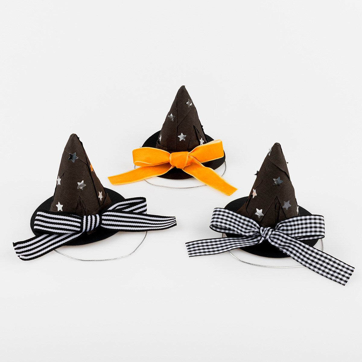 Three Halloween-themed witch hats with decorative bows on a white background