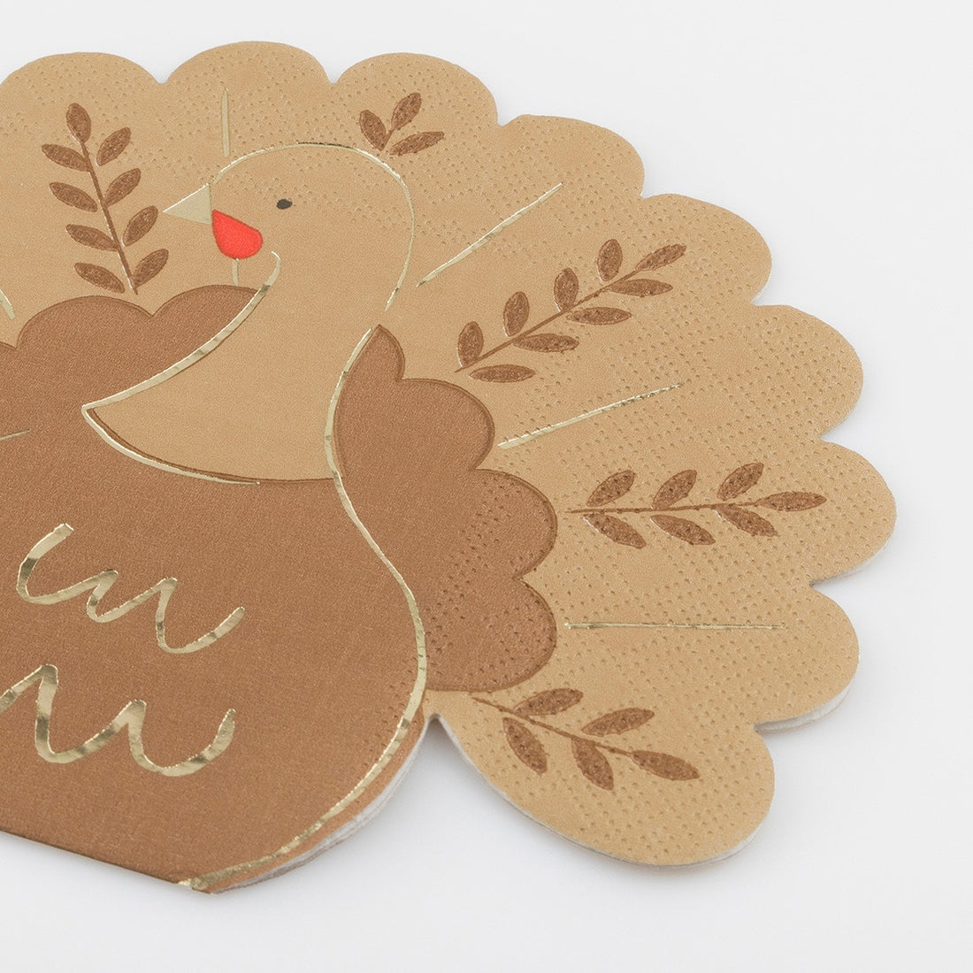 A close-up of a paper napkin shaped like a turkey with gold accents. 