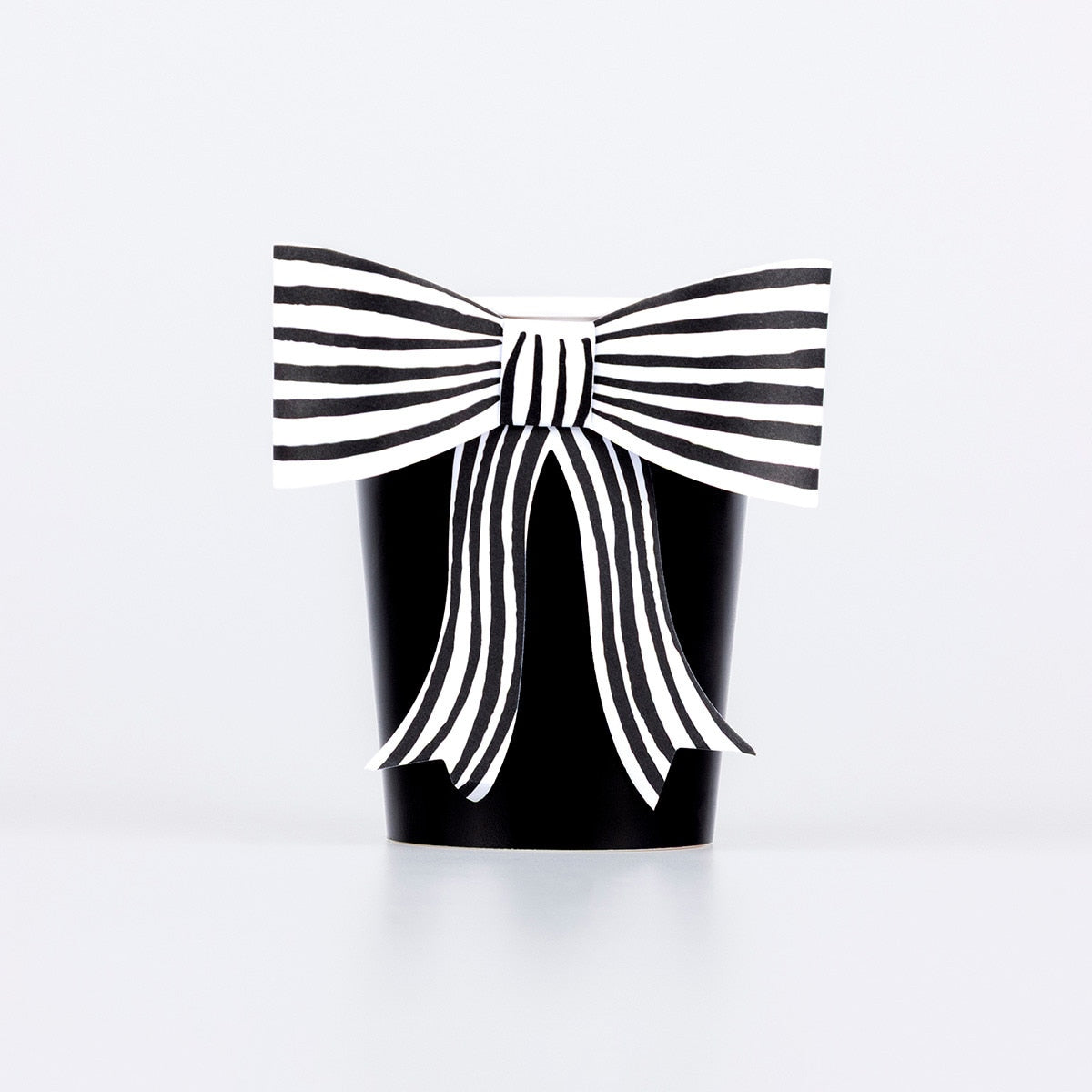 Black paper cup with a black and white striped paper bow attached to it. 