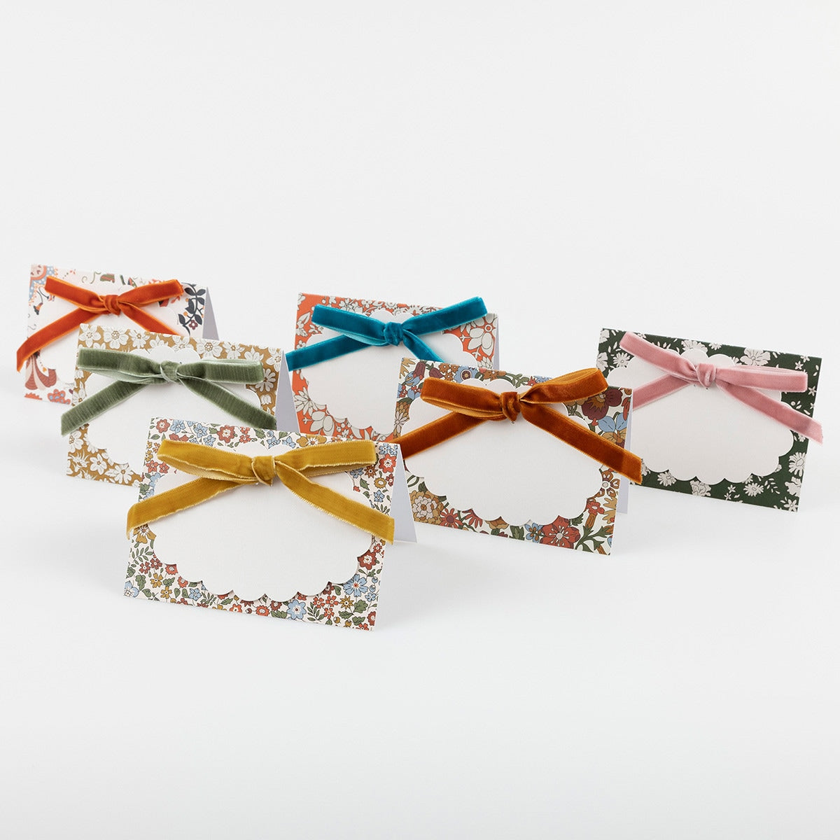 6 paper place cards featuring 6 different Liberty floral prints in warm fall colors. 
Each is decorated with a luxurious velvet bow in burnt orange, muted gold, teal, sage, berry red or dusty pink with pale matte gold foil details.  Each place card comes with a scalloped paper tag for you to write the name on. 