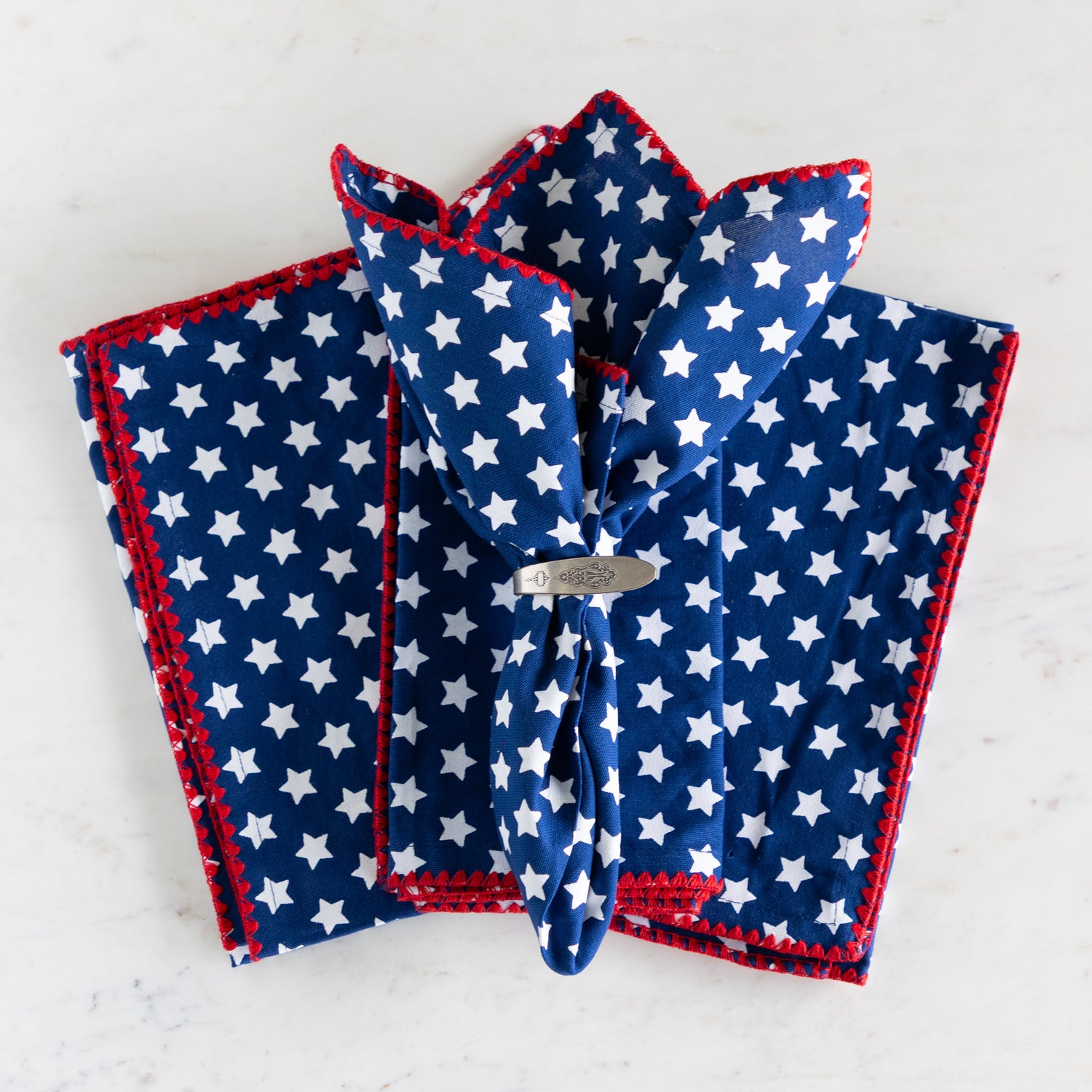 Three blue napkins with white star patterns on a light gray background.