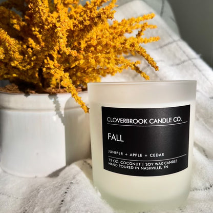 Cloverbrook Candle Co., Fall candle near a plant, on a blanket.