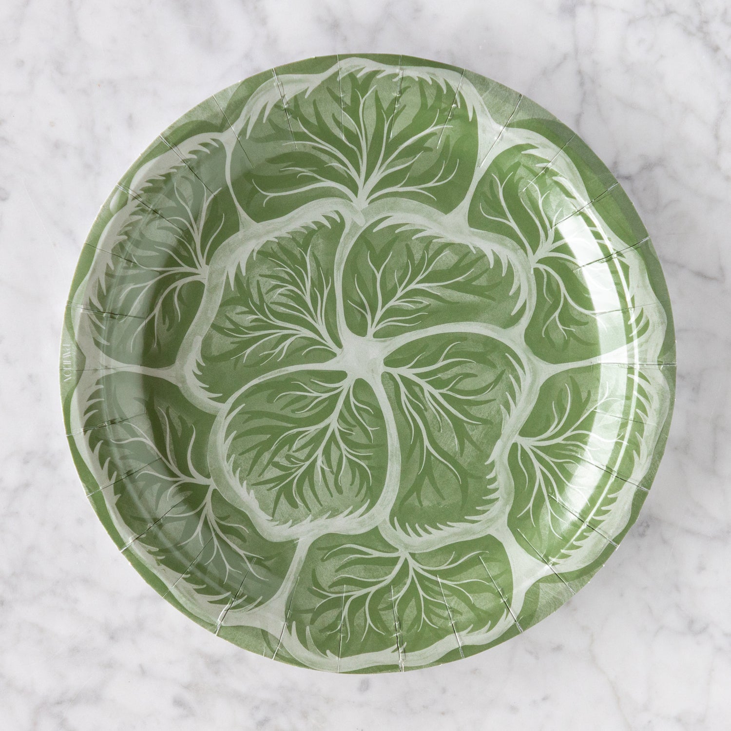 Green cabbage design paper plate on a marble table.