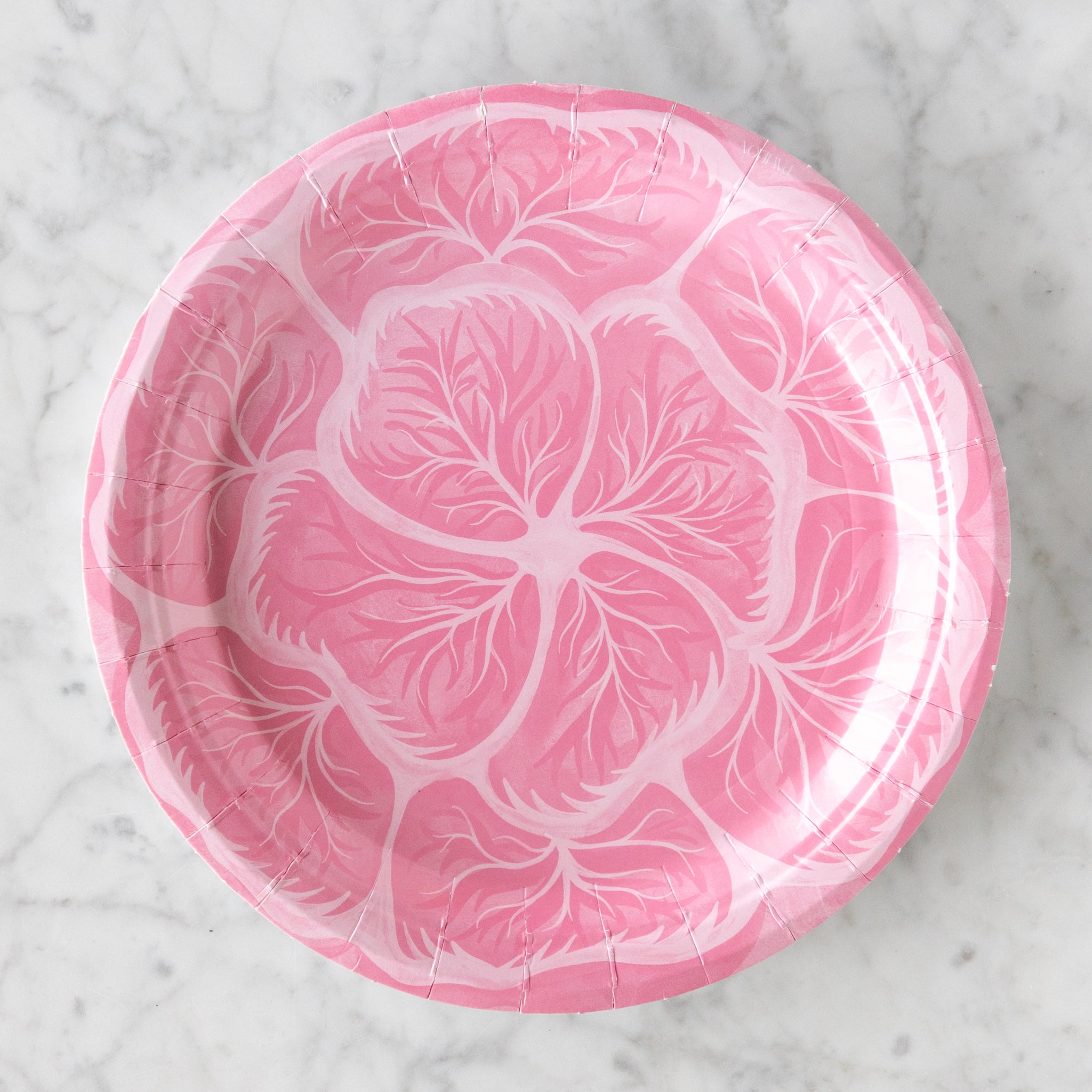Pink cabbage design paper plate on a marble table.
