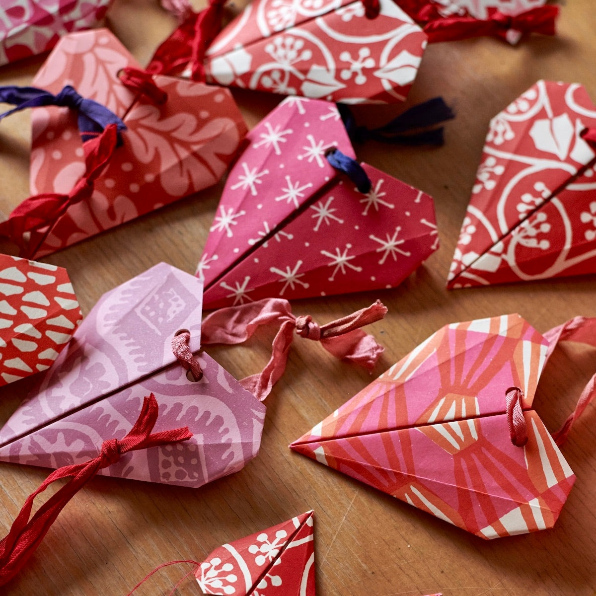 Red and pink origami hearts being crafted. 