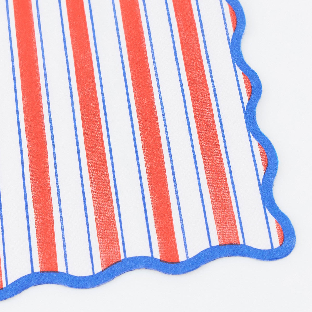 Close-up of a red, white, and blue striped paper napkin with scalloped edges on a white background.