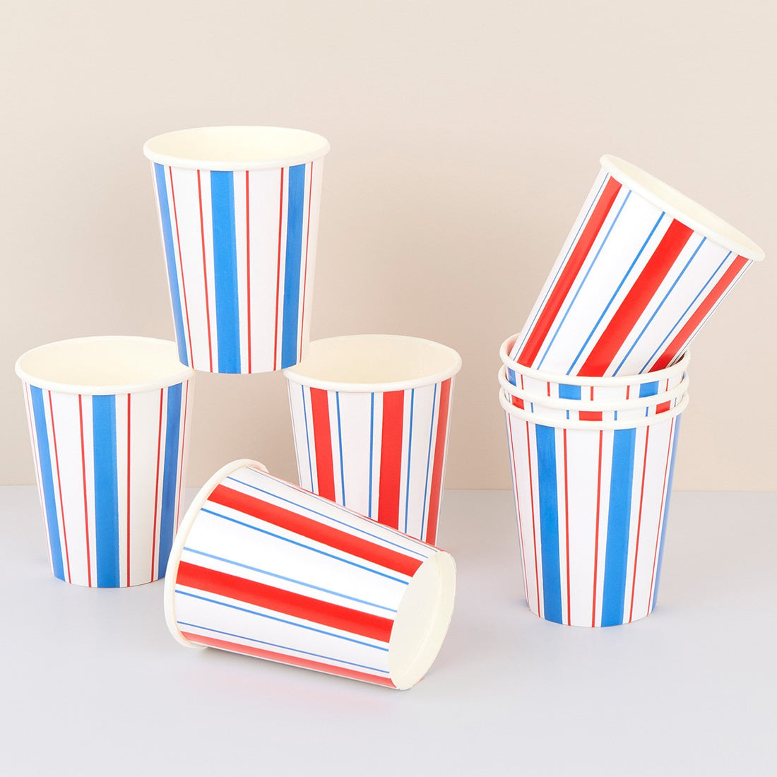 Set of red, white, and blue striped paper cups on a light background.