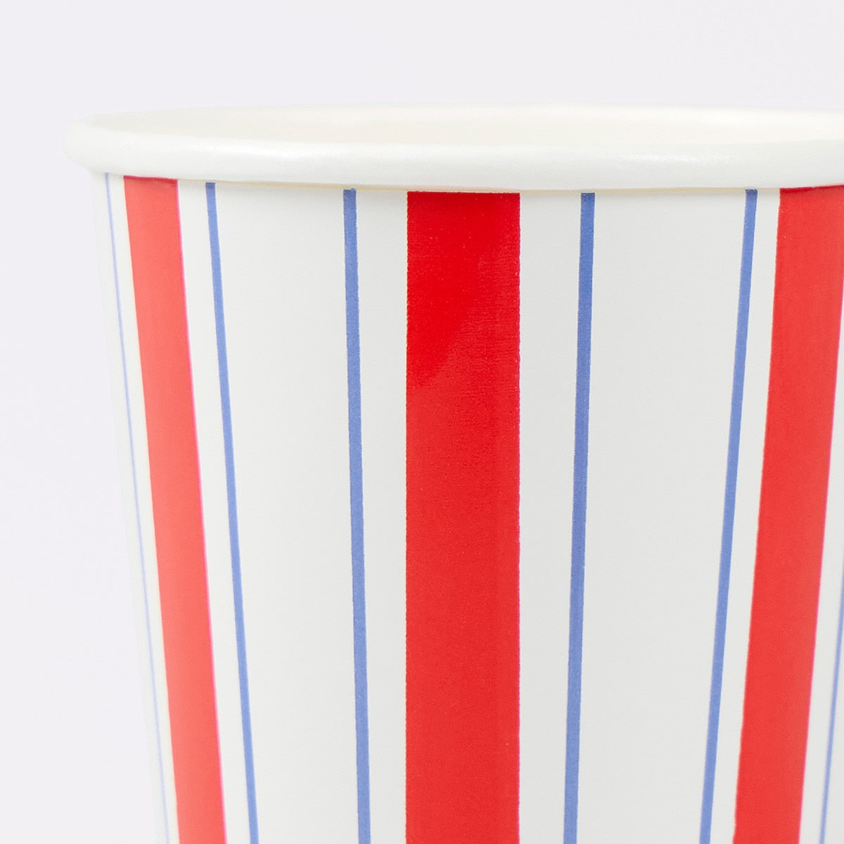 Close-up of a paper cup with red, white, and blue vertical stripes on a white background.