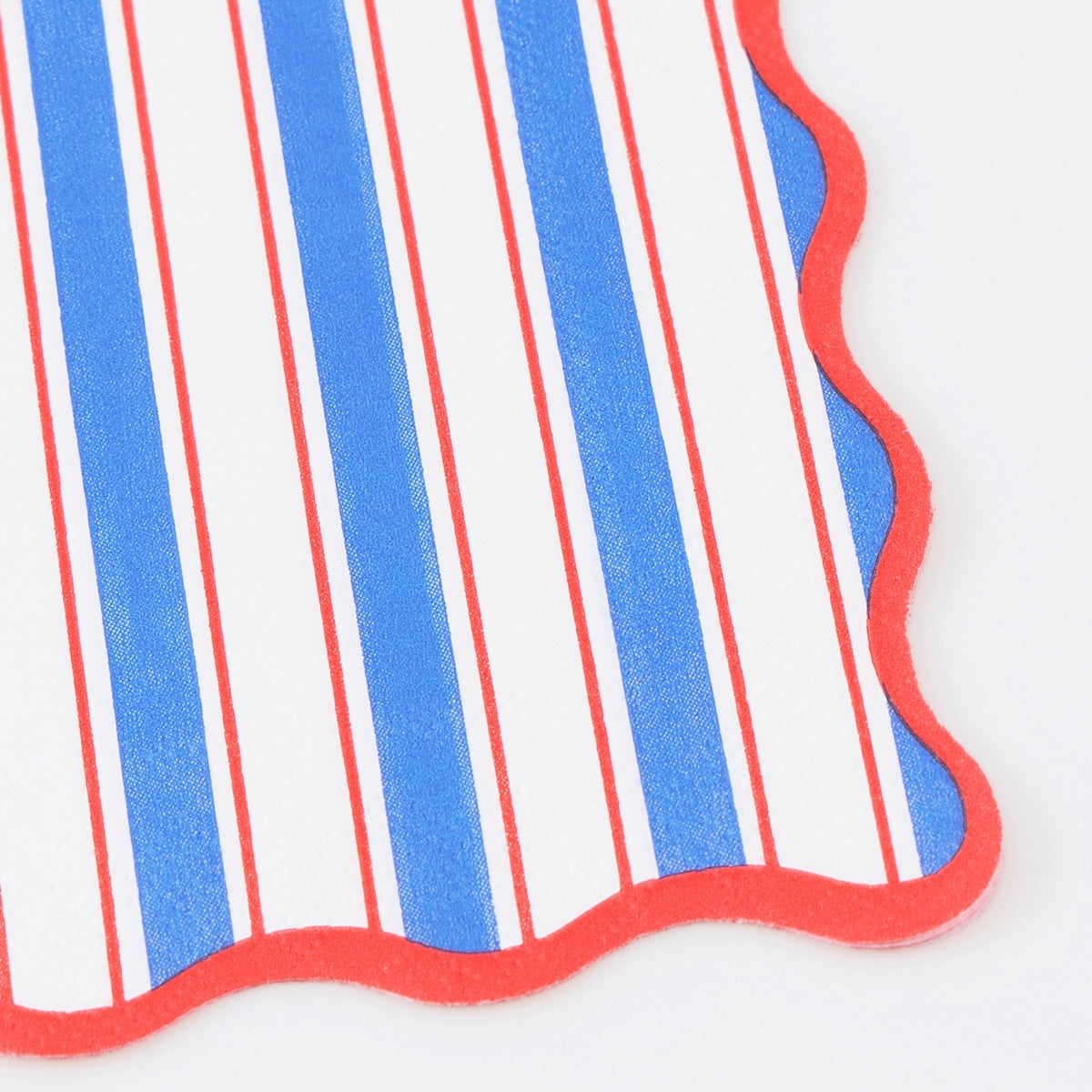 Close-up of a red, white, and blue striped paper napkin with a scalloped edge on a white background.