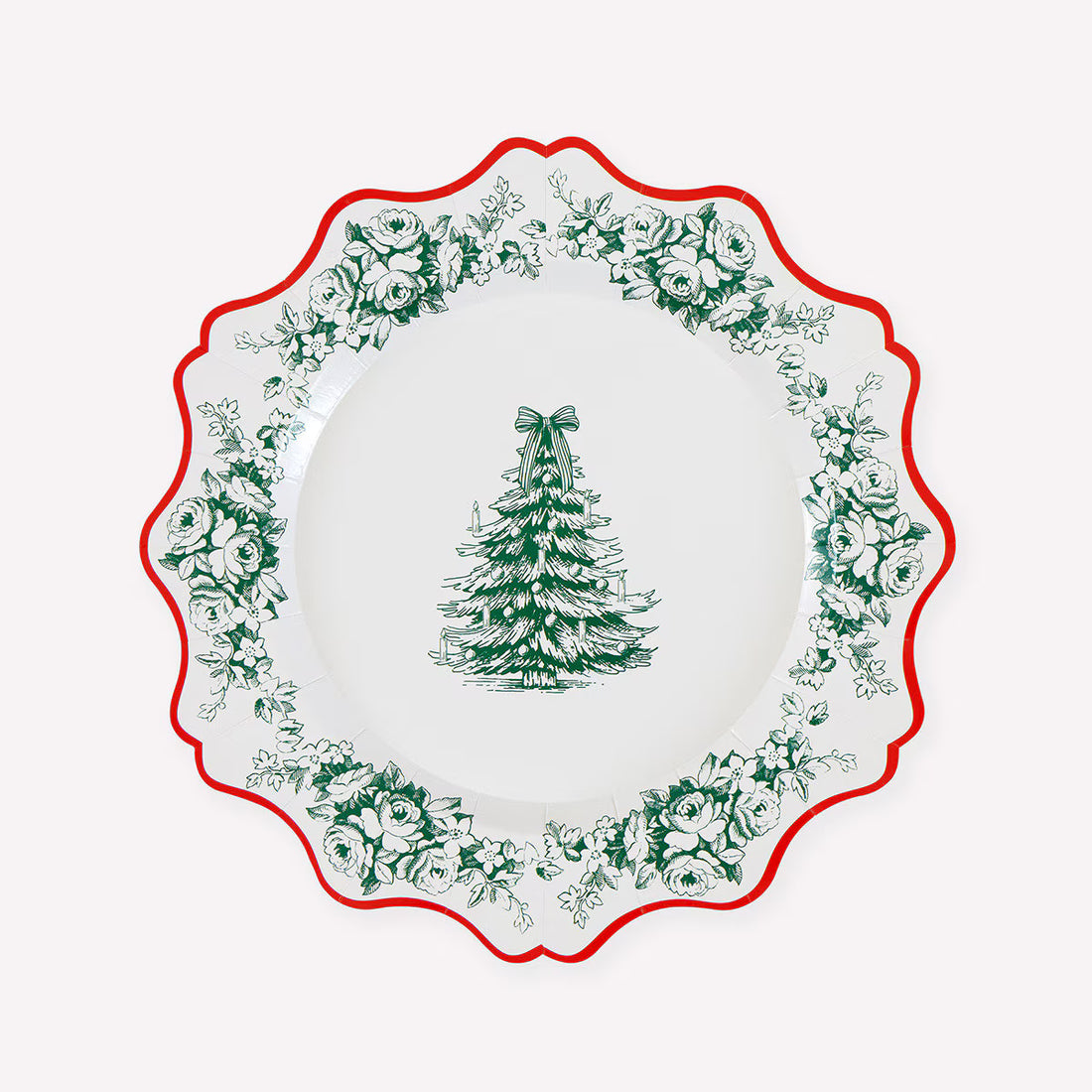A white paper Christmas plate with a scalloped rim, featuring a green tree of life motif in the center and a border of green floral and holly patterns, accented by a red rim.
