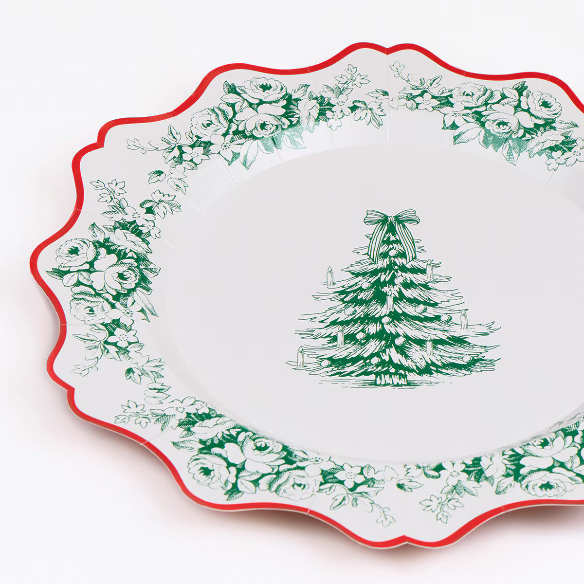 A white paper serving platter with a scalloped edge, featuring a green Christmas tree illustration in the center and a border of green floral toile-style print, finished with a thin red rim.