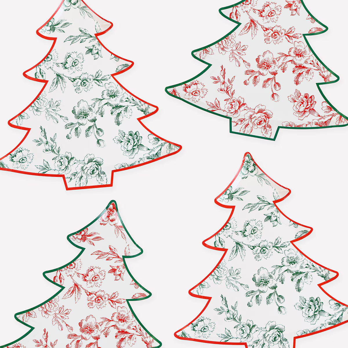 Four Christmas tree-shaped plates arranged on a white background, each with a floral toile-style print and contrasting tree outline in red or green.