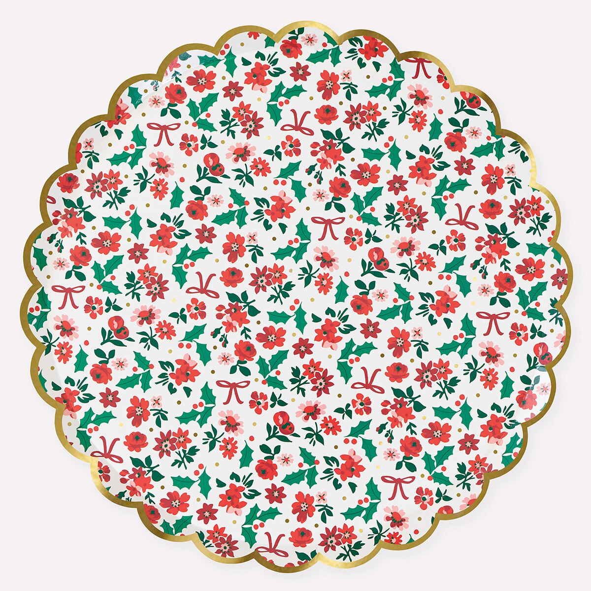 A round scalloped paper plate featuring a festive Christmas pattern of red flowers, green holly leaves, and red bows on a white background, finished with a gold metallic rim.