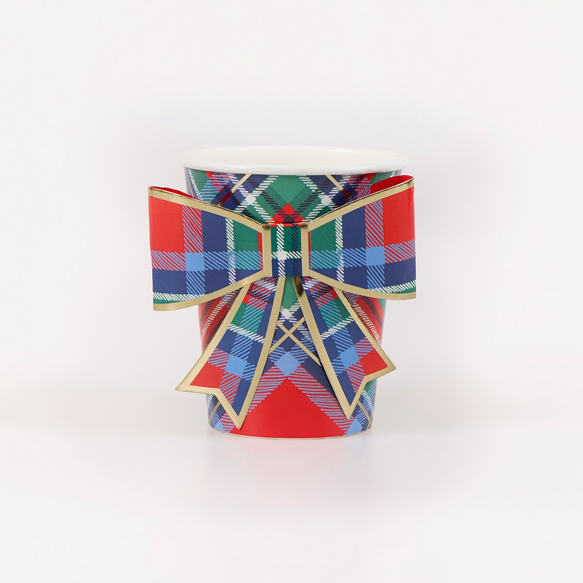 A paper coffee cup featuring a festive red, green, and blue tartan plaid pattern, adorned with a matching large bow outlined in gold trim, shown on a plain white background.