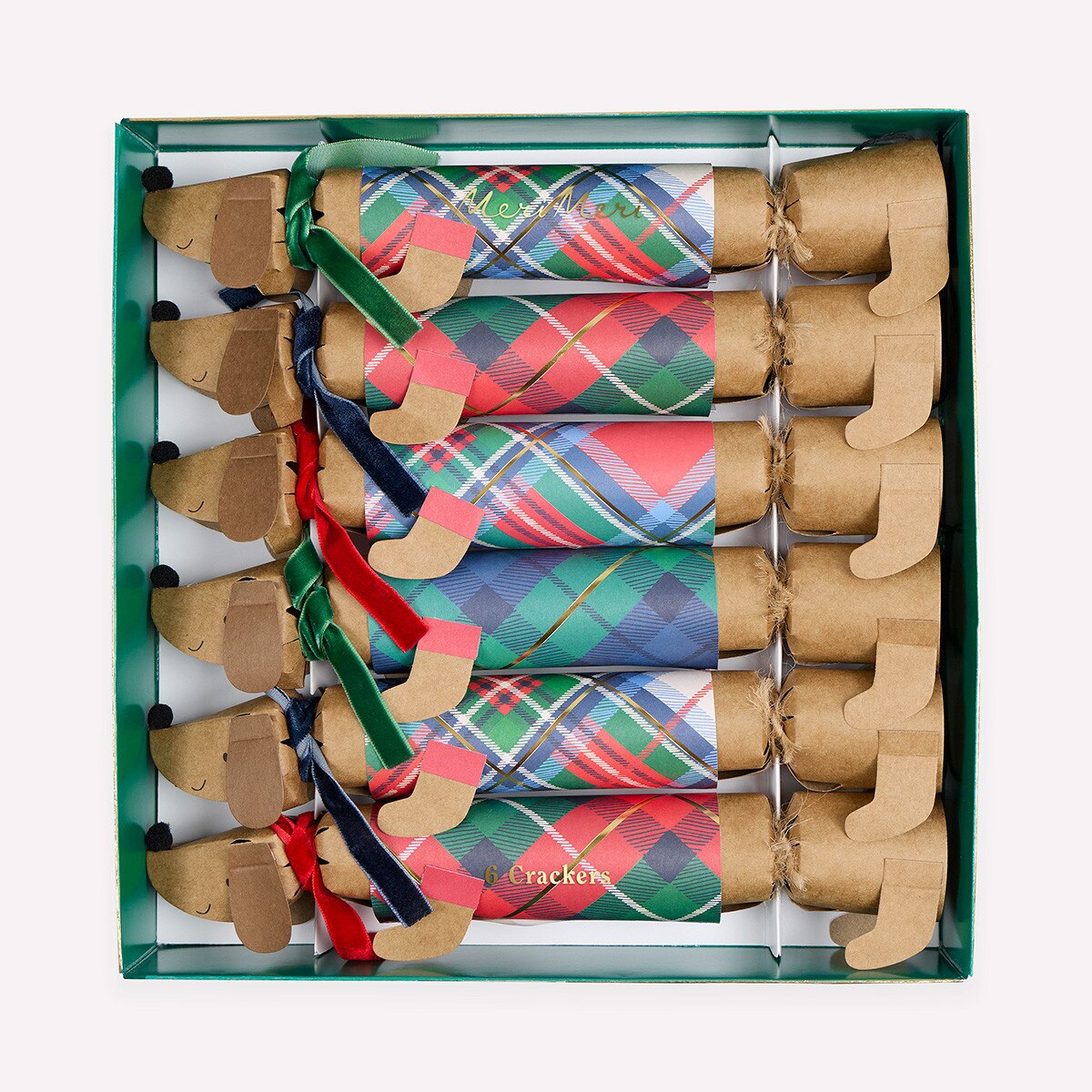 A boxed set of dachshund-shaped paper cracker ornaments with colorful plaid patterns and ribbon accents, arranged inside a green gift box on a light gray background.