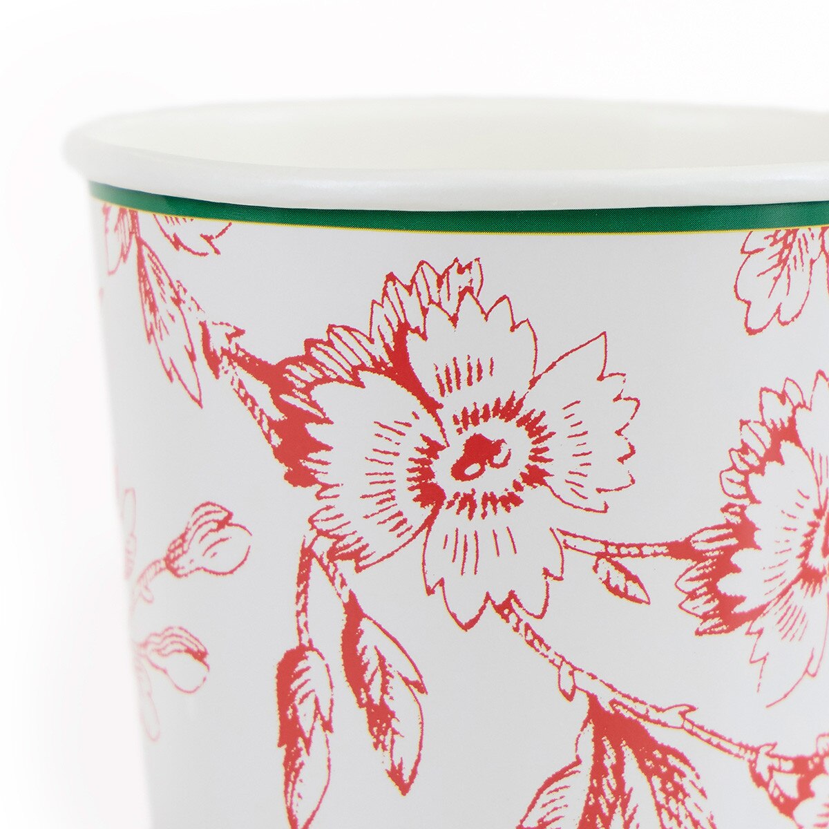 Close-up of a white cup or tumbler with a red floral line pattern and a thin green band around the rim, photographed on a white background.