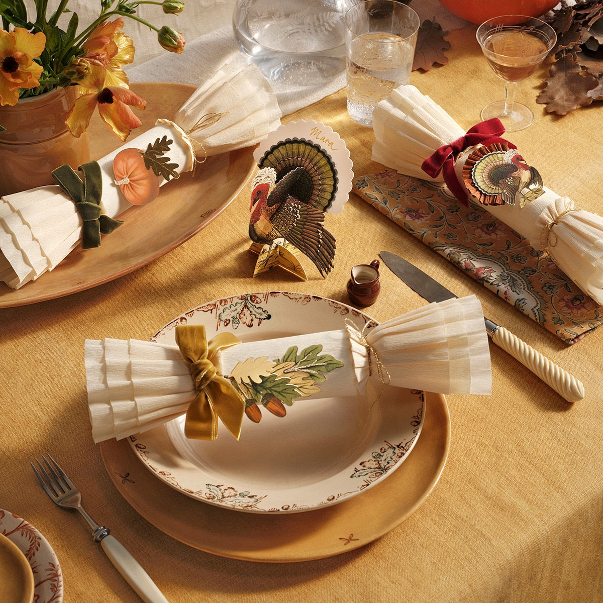 Thanksgiving table setting with decorative plates, napkins, and centerpieces on a yellow tablecloth.