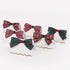 Six white paper place cards with wavy gold borders, each decorated with a ribbon bow in a tartan plaid pattern. The bows feature red, green, blue, and yellow plaid designs, with one bow in navy blue and red plaid and another in red and green plaid.