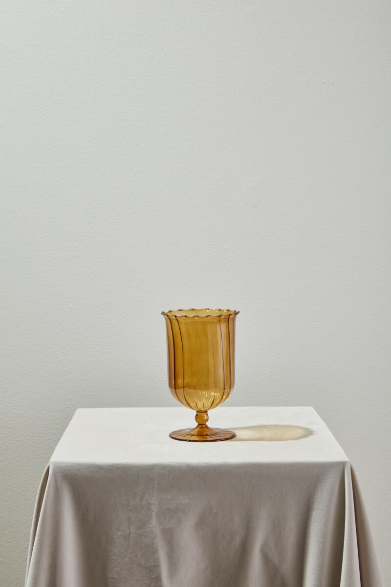 Amber glass vase on a white tablecloth with a plain background