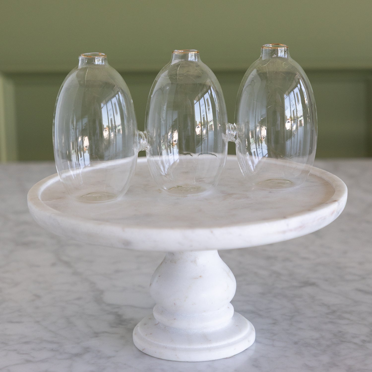 Vase with 3 cylindrical sections that are all attached together.  The vase is on a marble pedestal.   