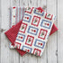 Collection of fabric tea towels with red, white, and blue patterns on a wooden surface.