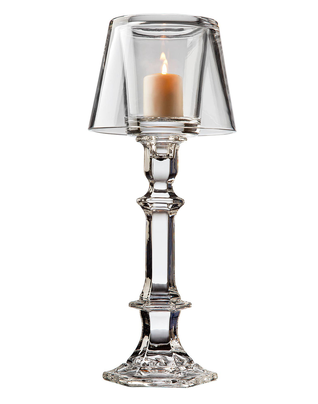 A lit candle inside a non-leaded crystal Godinger hurricane lamp placed on top of a silver candlestick holder.
