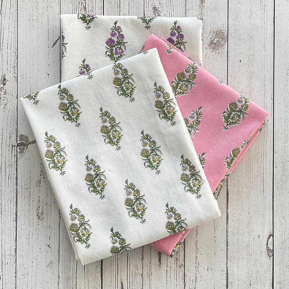 Two fabric swatches with floral patterns on a wooden surface