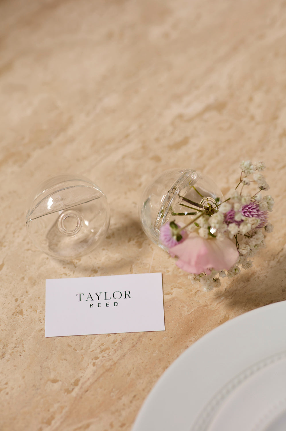 Decorative glass vases with flowers on a beige surface, name card &