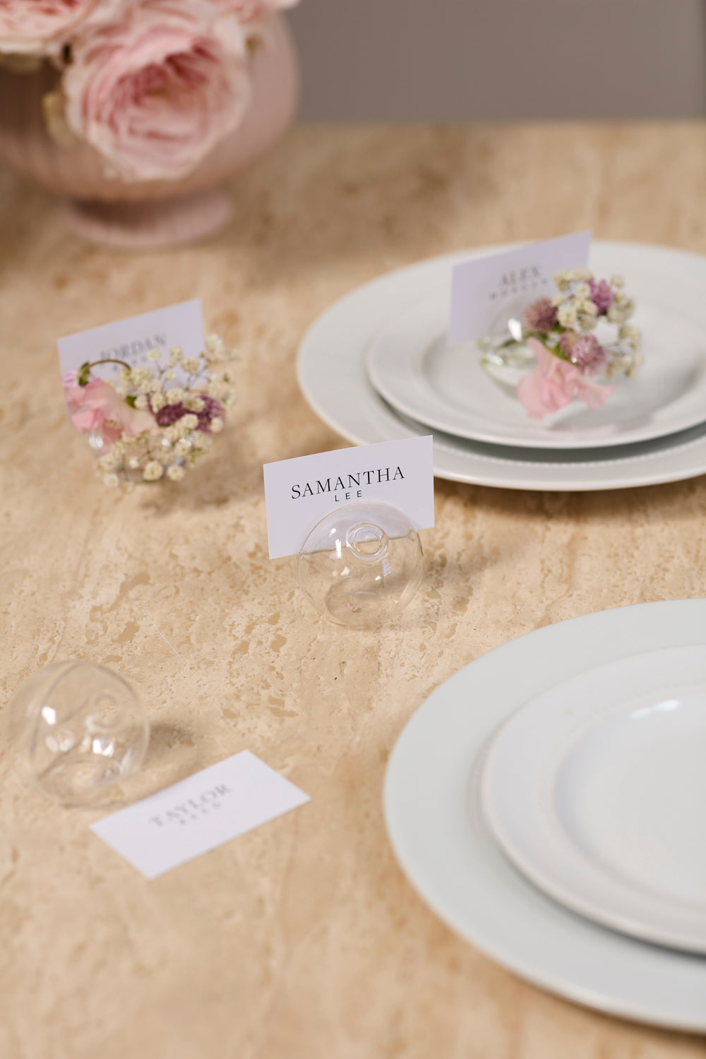 Table setting with floral place cards and name tags on a beige tablecloth.